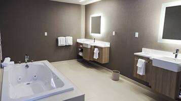 A modern bathroom with a large bathtub, two sinks, and wooden cabinets.
