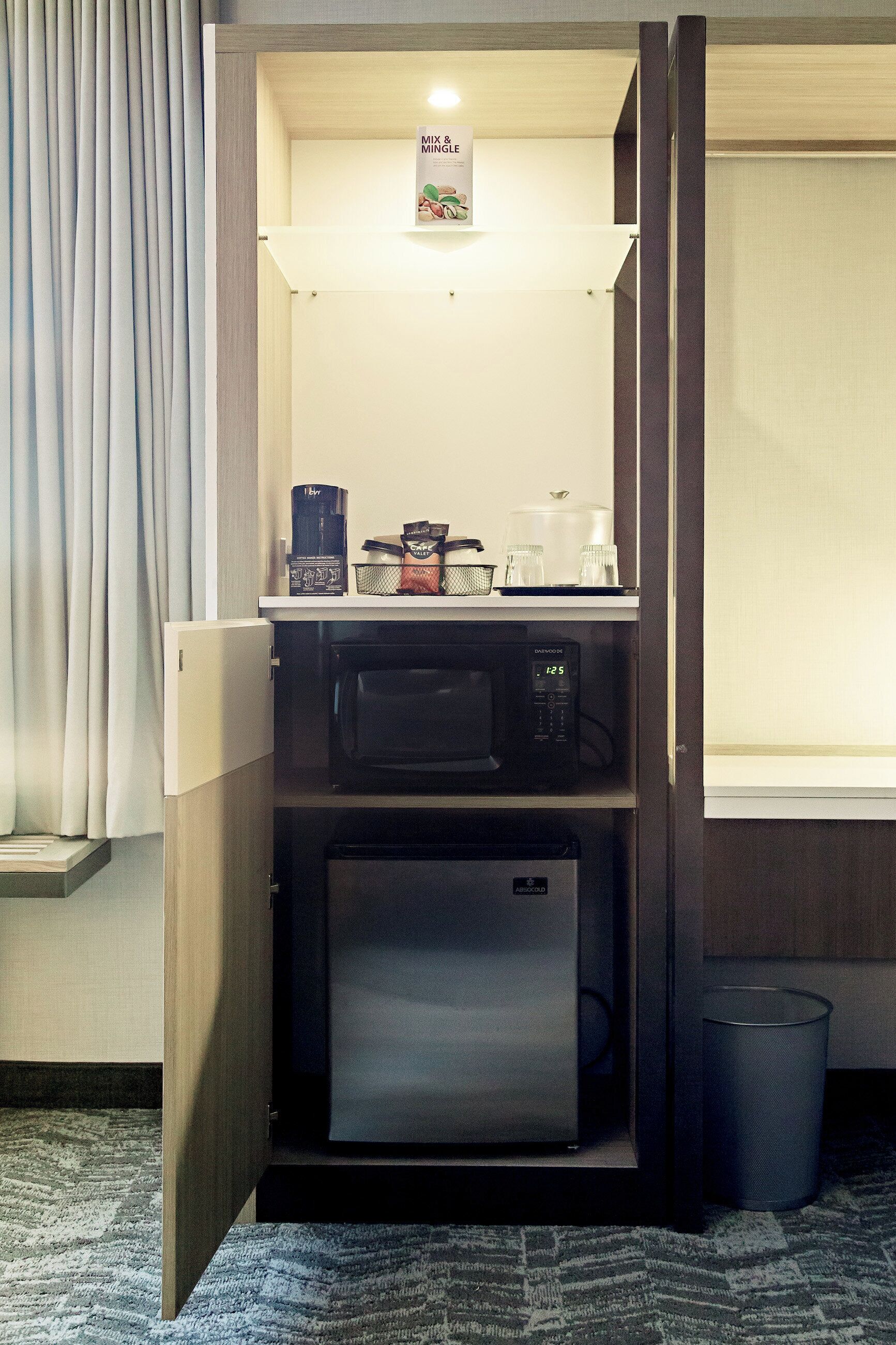 A compact kitchenette with a microwave, coffee maker, and a small refrigerator.
