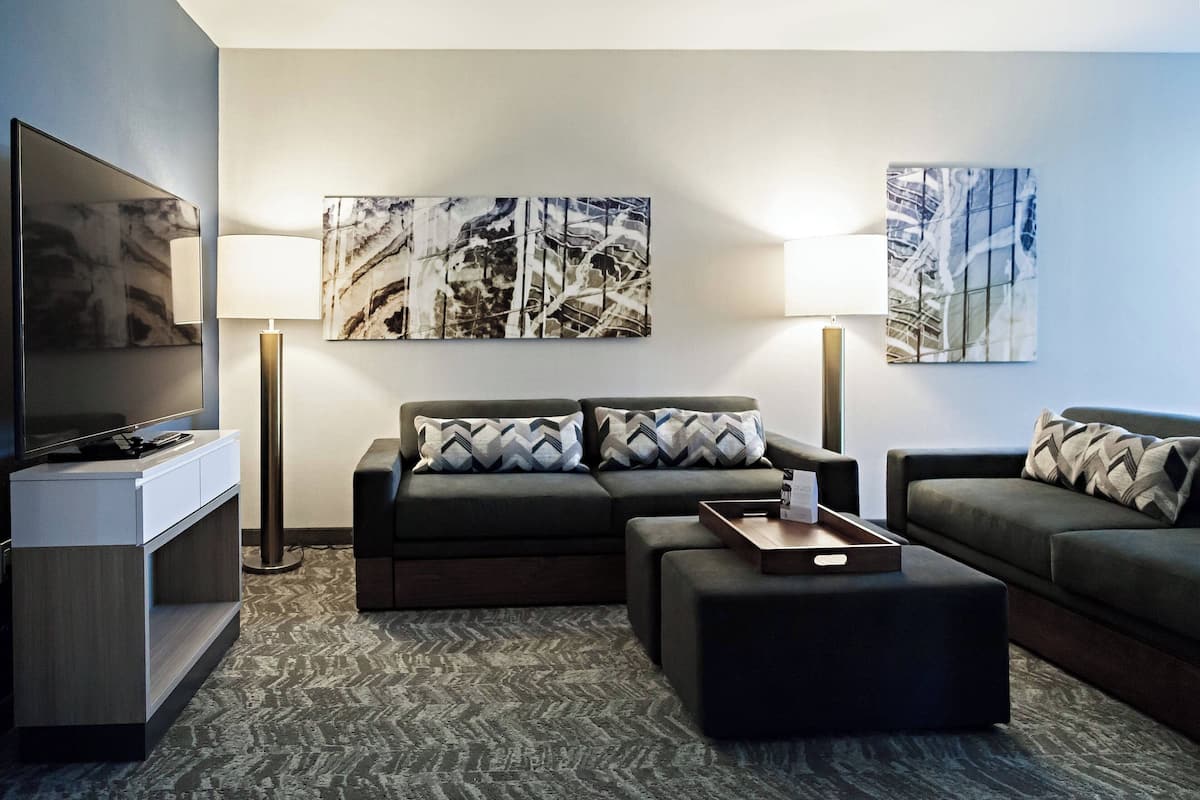 A modern living room with a sectional sofa, a flat-screen TV, and abstract wall art.