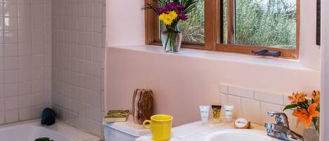 A bathroom with a bathtub, a sink, and a window with a view of trees.