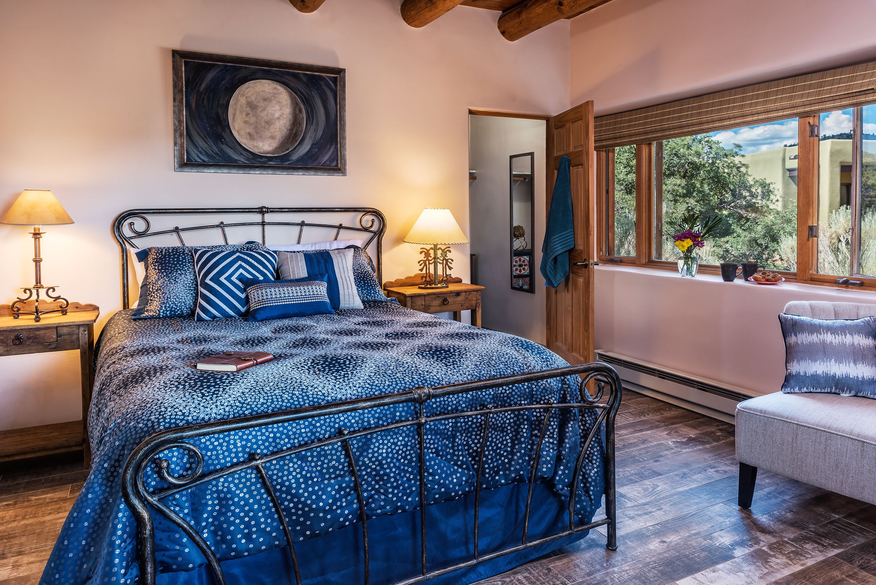 A bedroom with a bed, two bedside tables, a nightstand, a window with a view, and a chair.