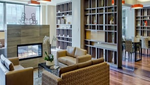 A modern lounge area with a fireplace, comfortable seating, and a large bookshelf.