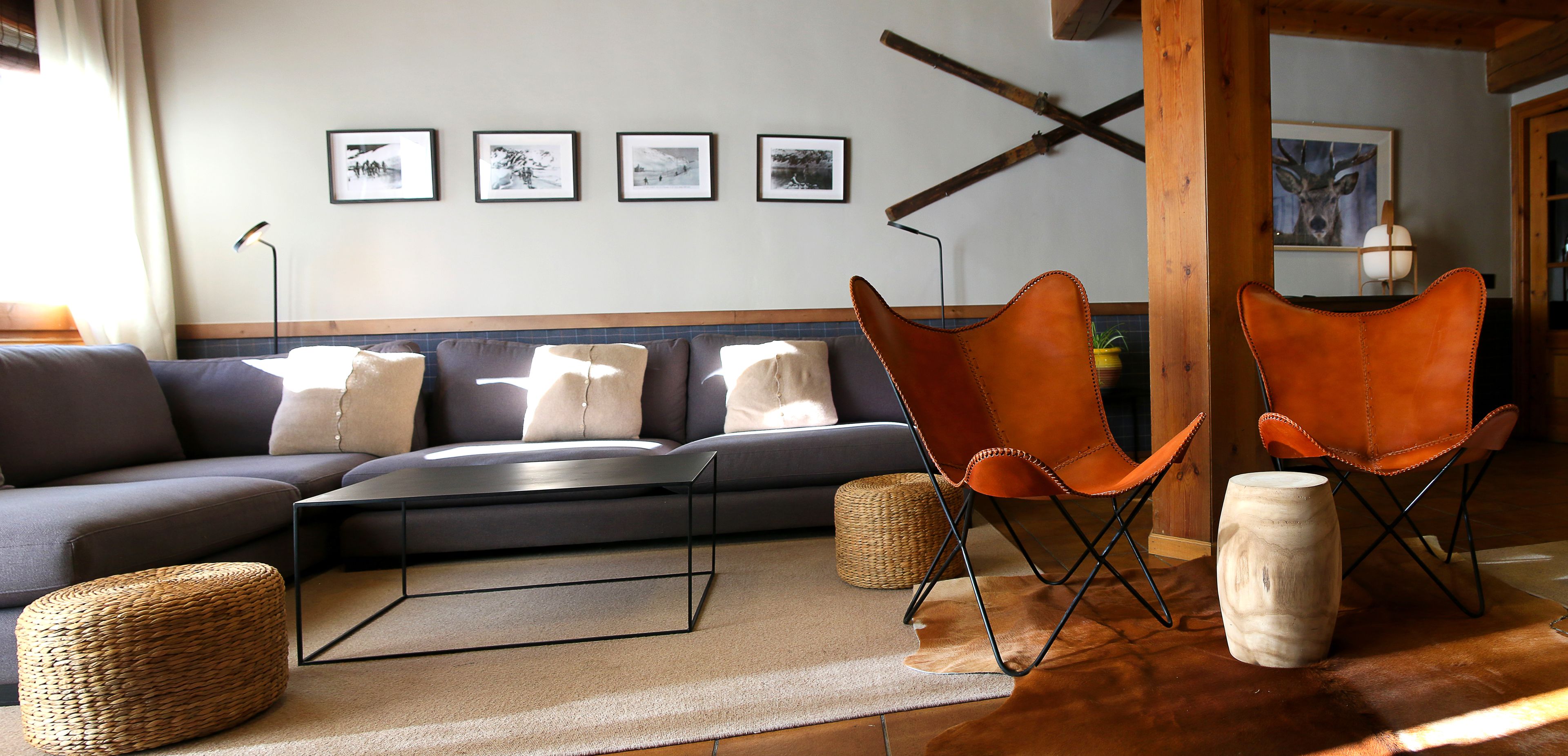 Una sala de estar moderna con un sofá, dos sillones de cuero, una mesa de centro y una alfombra.