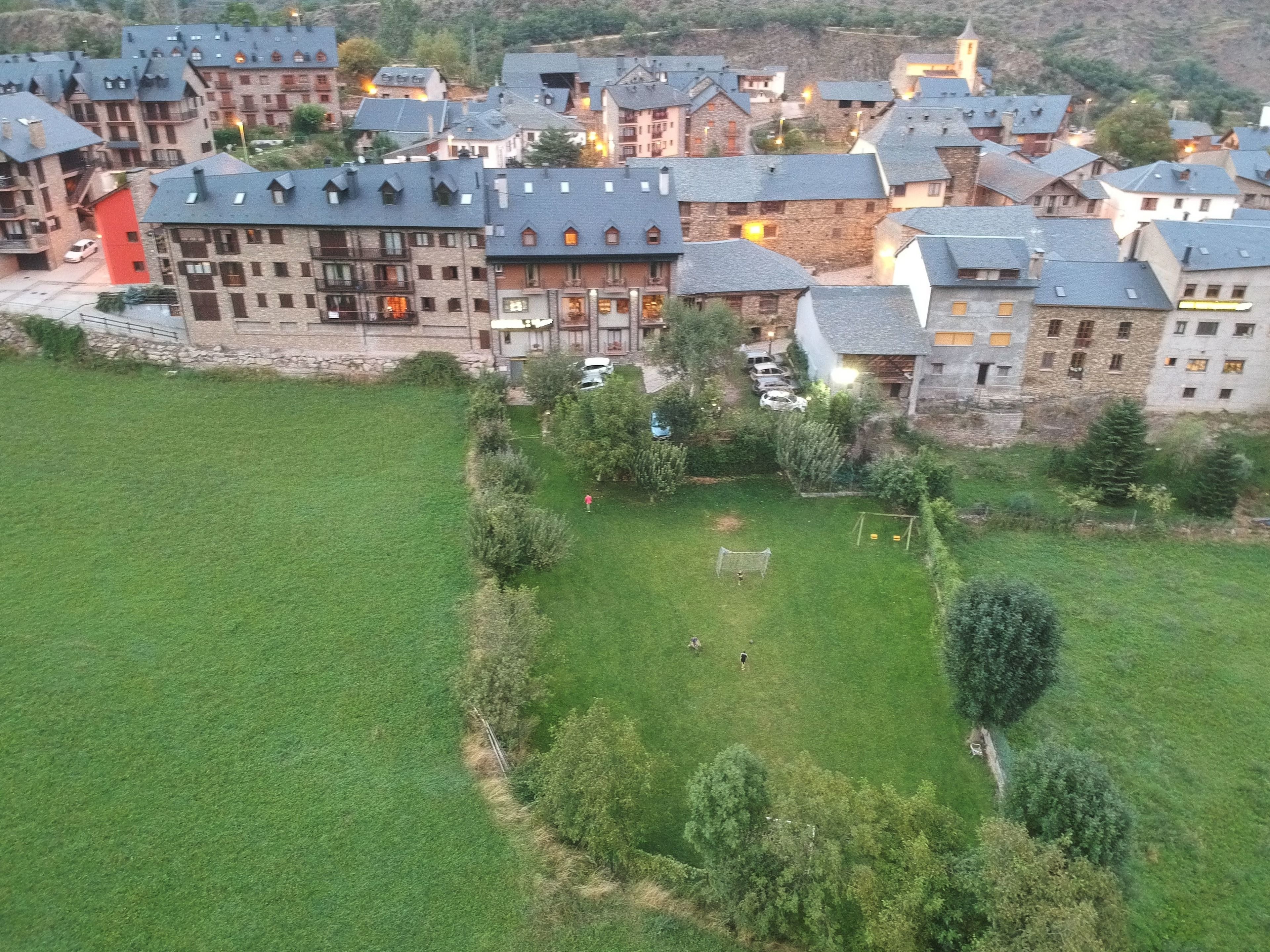 Uma área residencial com vários edifícios, um campo gramado e algumas árvores.