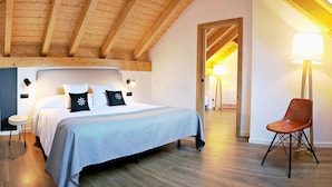 Un dormitorio con una cama grande, vigas de madera en el techo, una silla y una lámpara.