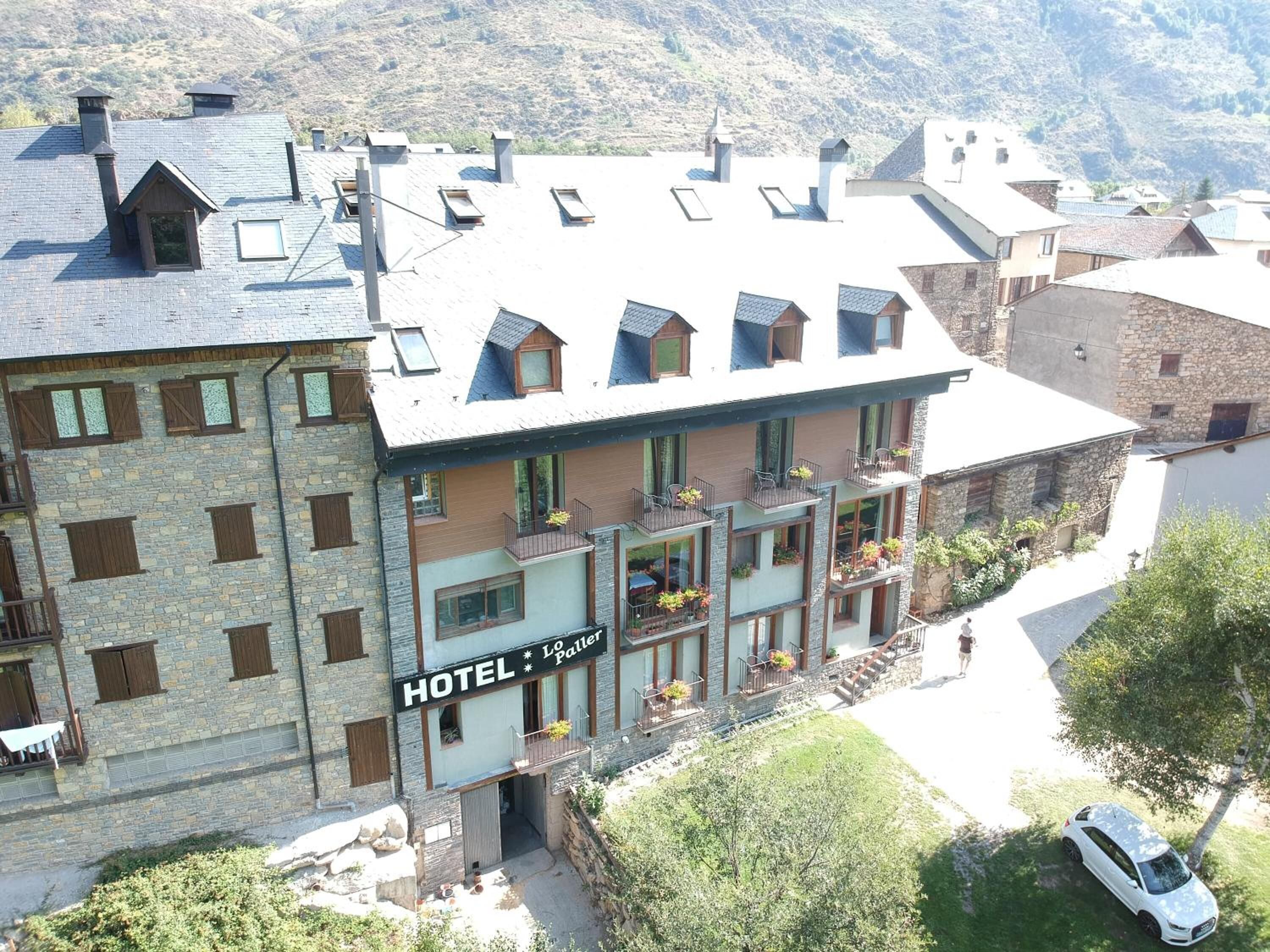 Un hotel con varios balcones, fachada de piedra y un letrero que dice "HOTEL * Lo Patter".