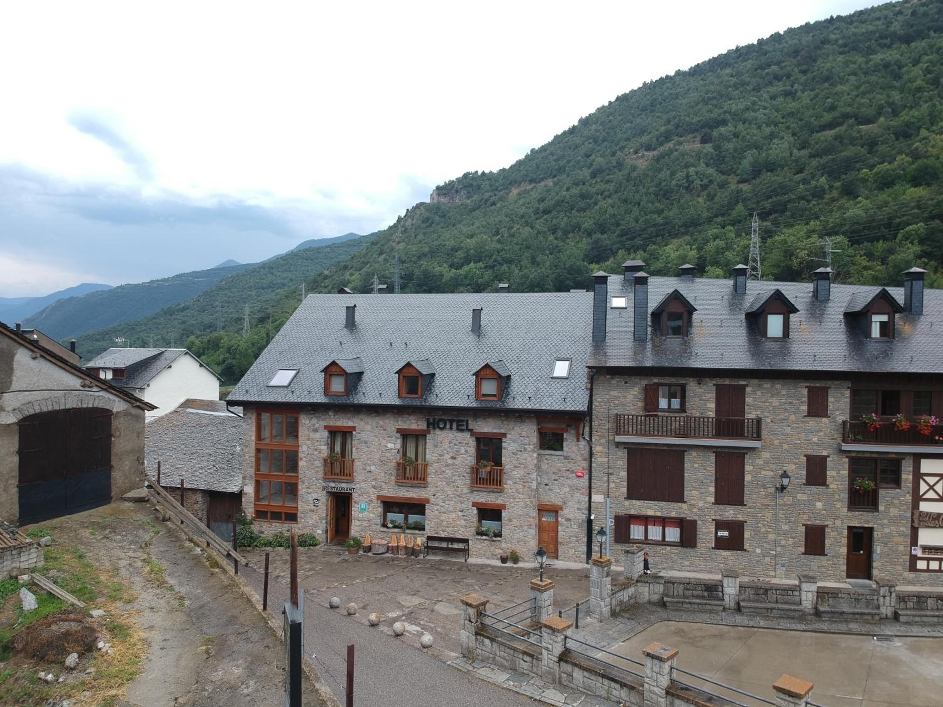 Un edificio de piedra con restaurante y hotel. Tiene techo inclinado y varias ventanas.