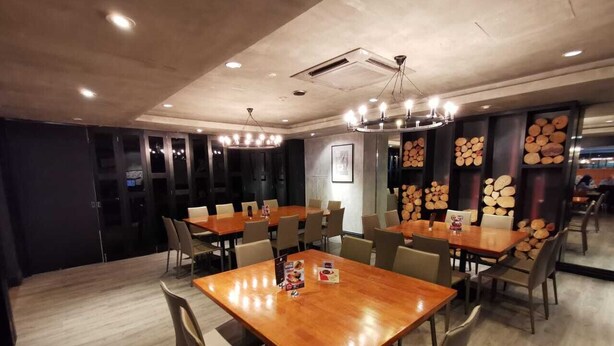 Un comedor moderno con mesas y sillas de madera, una araña y detalles decorativos en las paredes.