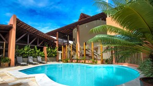 A swimming pool with a tiled deck, surrounded by lounge chairs and potted plants. - Vivá Barra Hotel Pousada (Barra de São Miguel)