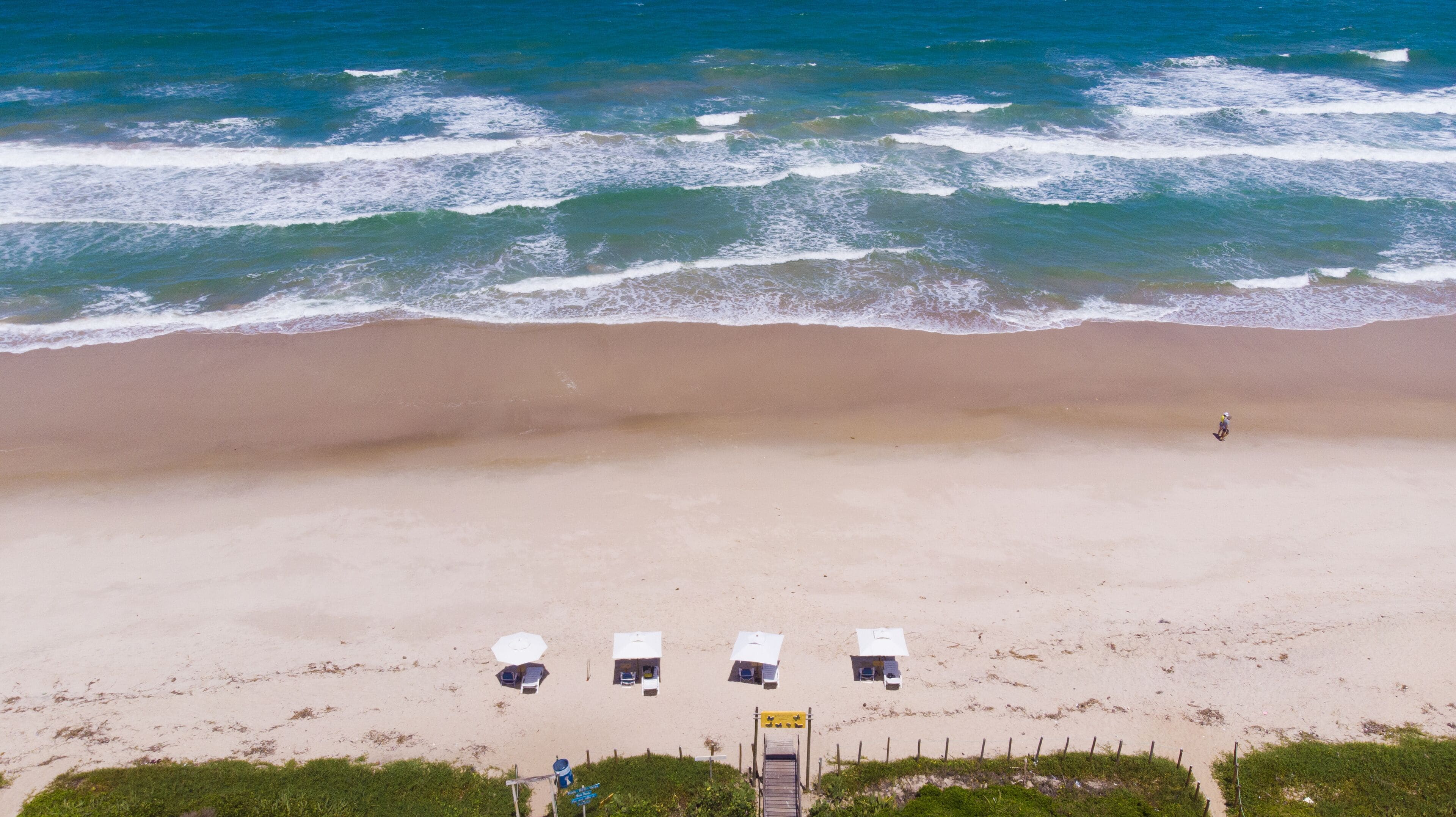 Perto da praia, areia branca, espreguiçadeiras, guarda-sóis 