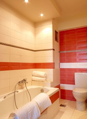 A bathroom with a bathtub, a toilet, and red and white tiles. - Villa Artemis (Rhodes)