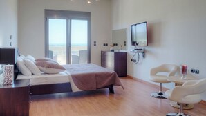 Et moderne hotelværelse med seng, skrivebord, fjernsyn og en balkon med udsigt.