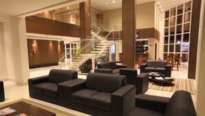A modern lobby with a staircase, seating area, and a bar. - Hotel Caiuá Cascavel (Cascavel)