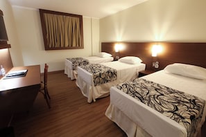 Una habitación de hotel con dos camas individuales, un escritorio con silla y televisión.