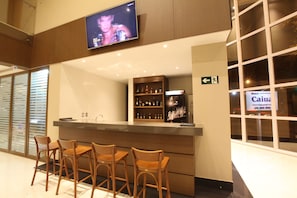Zona de bar con sillas de madera y una barra que exhibe botellas.