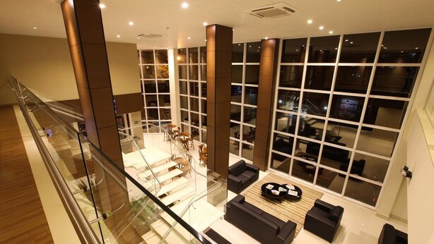 Un hall d’entrée moderne doté d’une rambarde en verre, d’un escalier et d’un espace détente avec des canapés et une table basse.