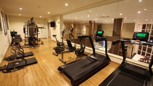 Une salle de sport équipée de tapis de course, de vélos elliptiques et de matériel de musculation.