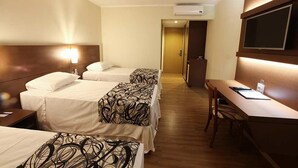 A hotel room with two beds, a desk, and a TV. - Hotel Caiuá Cascavel (Cascavel)
