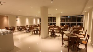 Un restaurant spacieux, doté de nombreuses tables et chaises, de grandes fenêtres et d’un intérieur propre et moderne.