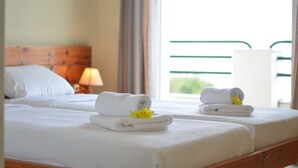 A hotel room with two beds, each with neatly folded white towels and a small yellow flower. - Akti Anastasia (Corfu)