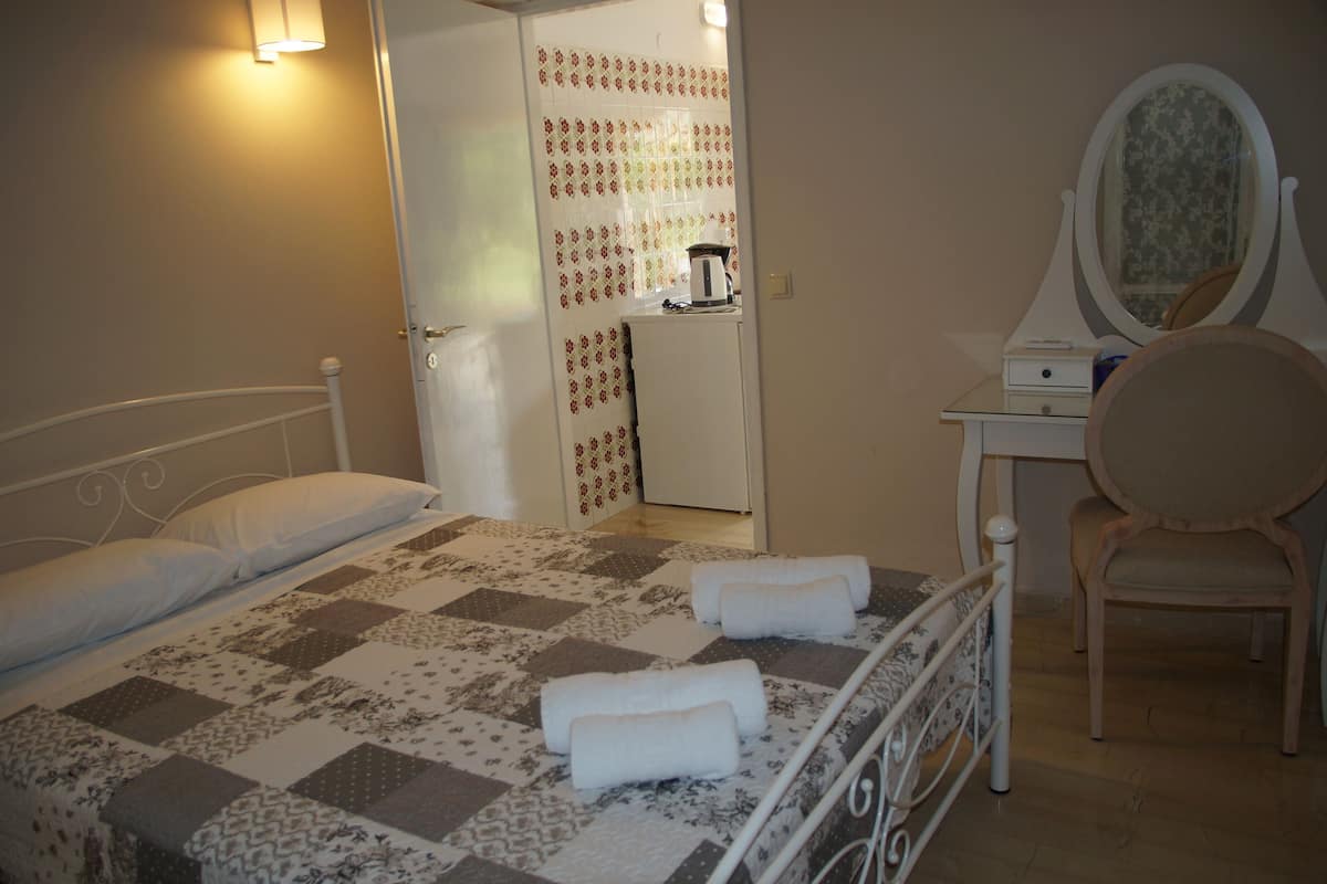 A bedroom with a bed, a chair, a dresser, and a mirror.