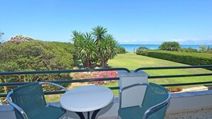 A balcony with a table and chairs, overlooking a well-manicured lawn and the ocean. - Akti Anastasia (Corfu)