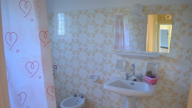 Un baño con papel tapiz floral, un lavabo blanco, un bidé y un espejo.