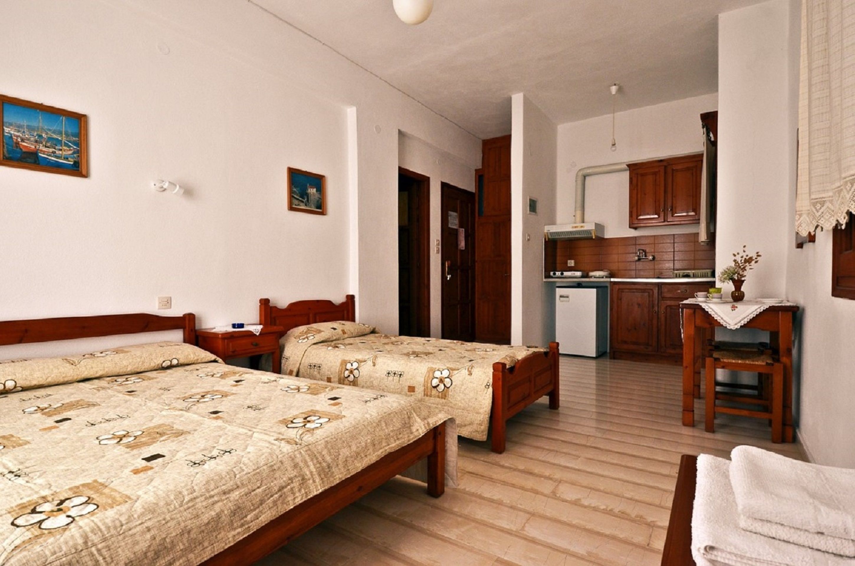 Une chambre avec deux lits, une petite table et, au fond, un coin cuisine.