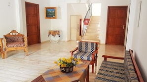 A living room with a wooden bench, a sofa, and a table with a vase of flowers. A staircase is visible in the background.