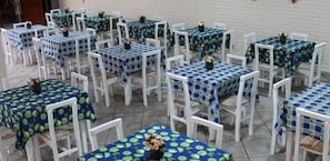 A series of tables with white chairs, each covered with a blue tablecloth featuring a green leaf pattern. - Rede Andrade Goiânia Centro (Goiânia)