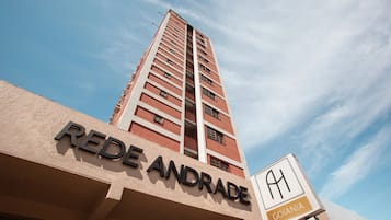 Um edifício alto com uma placa indicando 'REDE ANDRADE' e outra com 'GOIÂNIA'.