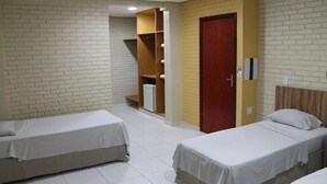 Habitación de hotel con dos camas individuales, un armario, un espejo y una puerta.