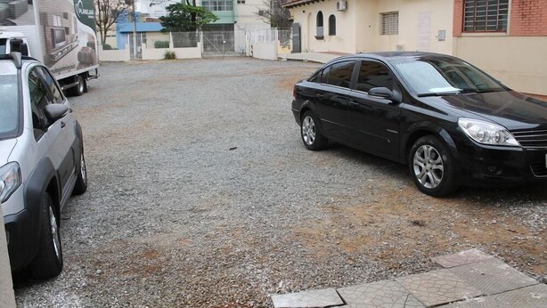 Un camino de grava con un coche negro estacionado a la derecha y un coche plateado a la izquierda.