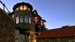 A stone building with a circular tower, a red-tiled roof, and a stone-paved courtyard. - Ta Petrina (Nafpaktos)