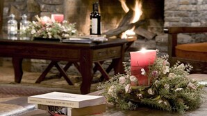 A cozy room with a stone fireplace, a wooden table with a candle, and a book. - Ta Petrina (Nafpaktos)