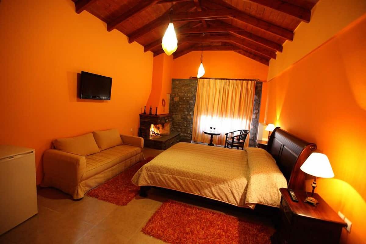 A cozy bedroom with a bed, a sofa, a small table, and a TV.