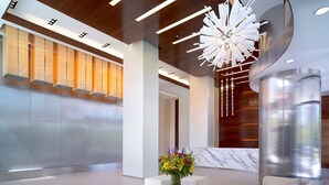 A modern lobby with a marble coffee table, a sofa, and a unique ceiling light fixture. - Global Luxury Suites at Columbus (Jersey City)