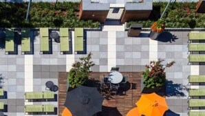 An outdoor seating area with multiple tables and chairs, surrounded by orange umbrellas. - Global Luxury Suites at Columbus (Jersey City)
