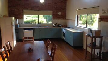 Una cocina con mesa, sillas, refrigerador, pileta y ventana.