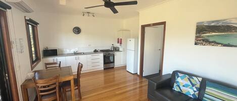 A compact living space with a dining area, kitchenette, and a sofa.