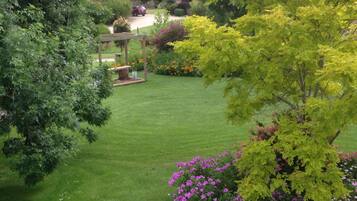 A well-maintained garden with a lawn, a wooden pergola, and flowering plants.