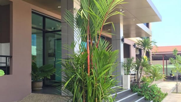 A modern building with a pool, surrounded by lush greenery and potted plants. - B Space Residence (Pattaya)