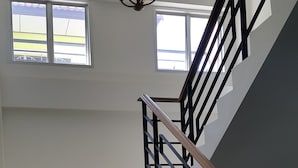 A staircase with black railings and wooden handrails, leading to an upper floor. - B Space Residence (Pattaya)