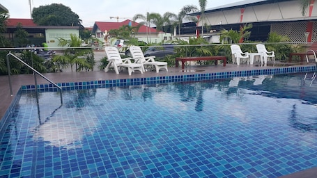 Una piscina al aire libre, sillones reclinables de piscina