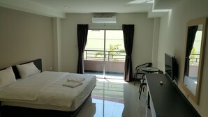 A hotel room with a bed, a desk, a chair, a television, and a balcony with a view. - B Space Residence (Pattaya)