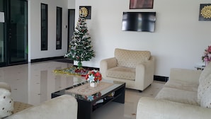 A modern living room with a Christmas tree, a sofa, a coffee table, and a flat-screen TV on the wall. - B Space Residence (Pattaya)