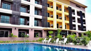 A multi-story hotel with balconies, a swimming pool, and outdoor seating. - B Space Residence (Pattaya)
