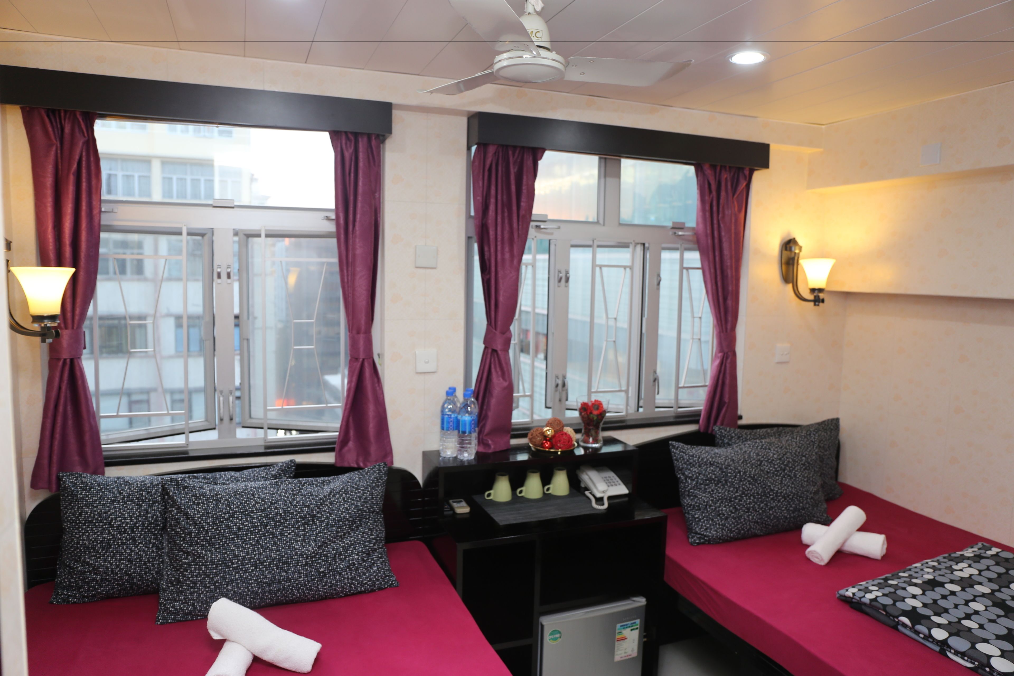 A hotel room with a bed, a desk with a phone, and a small fridge.