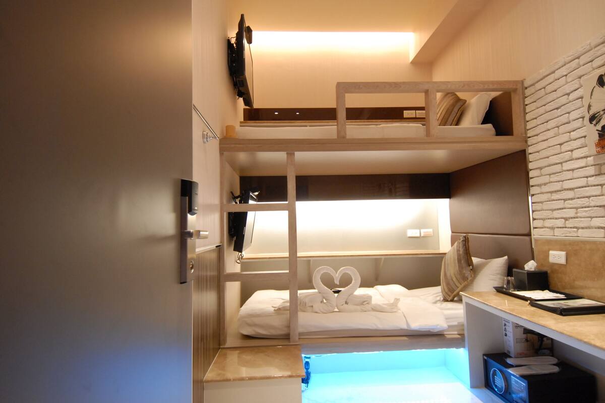 A bunk bed room with a desk and a small window.