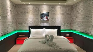 A hotel room with a large bed, two bedside tables, and a wall with repeated 'LOVE' text. - Kenting Starry Sky - Space Capsule (Hengchun)